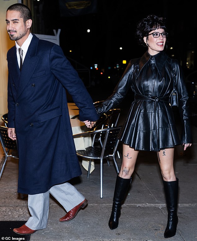 Ela juntou o vestido plissado de alto corte com um conjunto de botas de estilete de couro preto combinando e uma bolsa na mesma cor