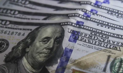 Cédulas de dólar e moedas de real, símbolo da variação cambial