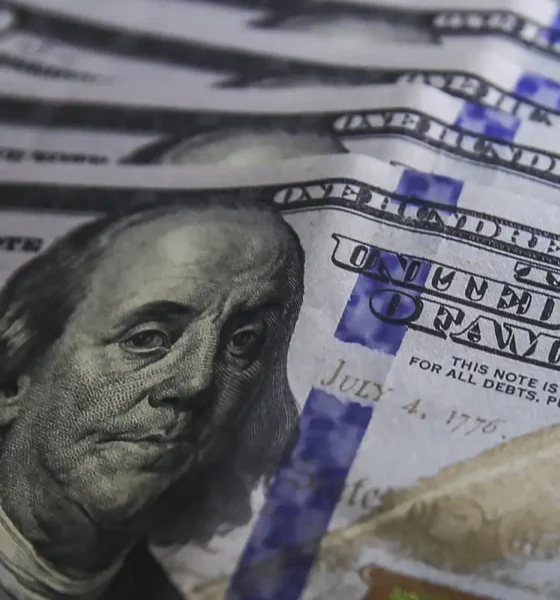 Cédulas de dólar e moedas de real, símbolo da variação cambial