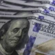 Cédulas de dólar e moedas de real, símbolo da variação cambial