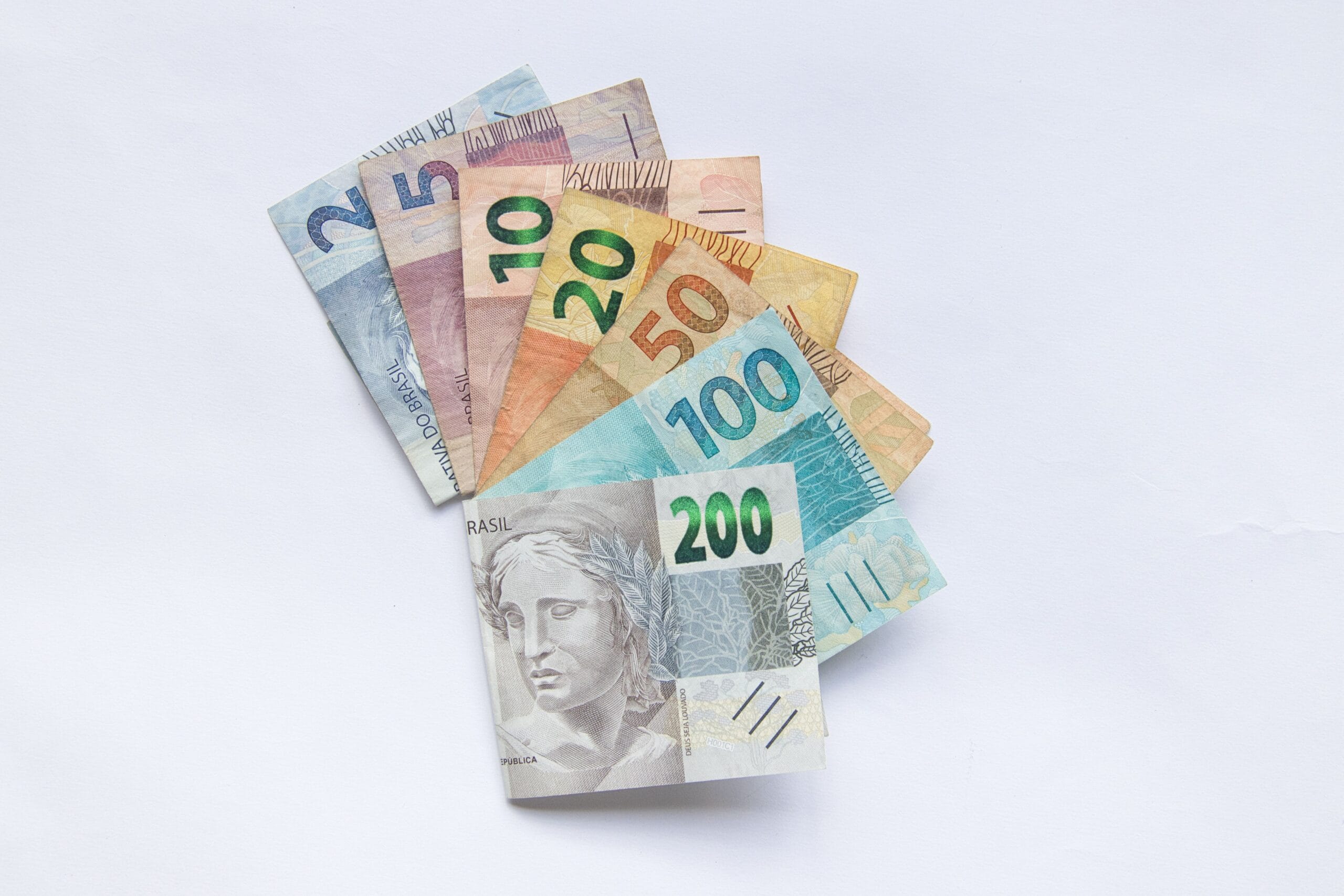 Cédulas de dinheiro brasileiro (real) dispostas em leque sobre fundo branco